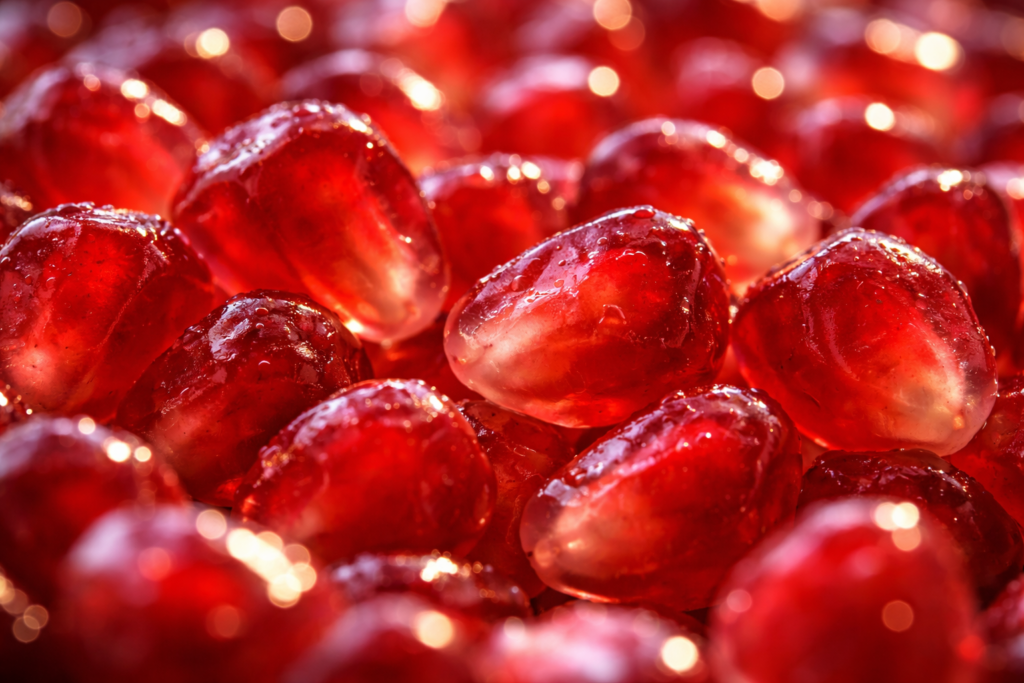 The image captures a close-up of juicy red pomegranate seeds.