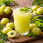 “A glass of amla juice surrounded by fresh Indian gooseberries, representing the Ayurvedic benefits of daily amla consumption for mental clarity and digestive wellness.”